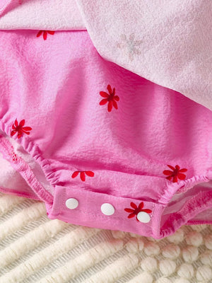 Pink cotton baby dress with red floral print and smocked details.