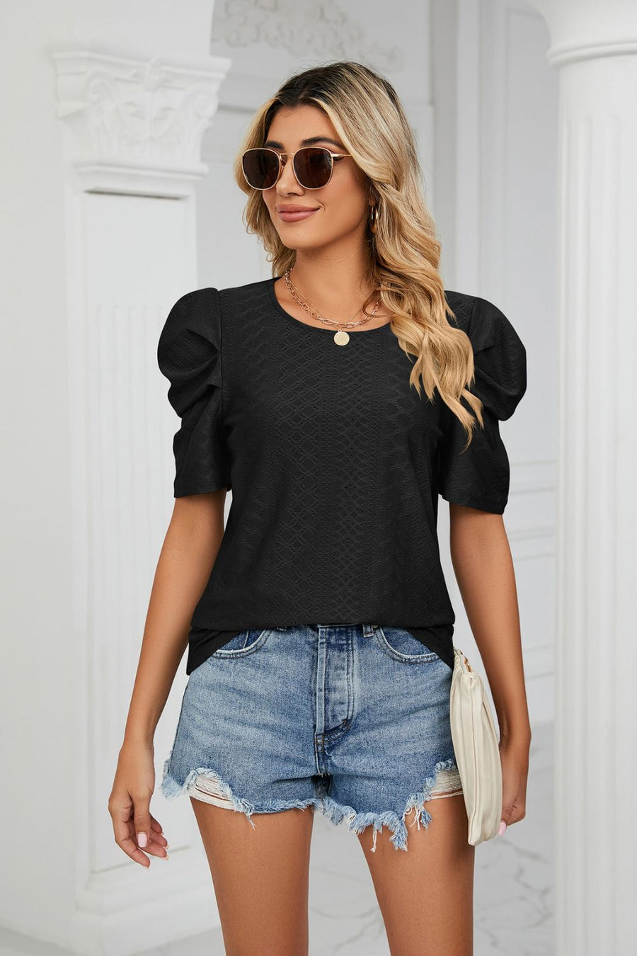 Black perforated sleeve volume top with textured fabric and round neckline.