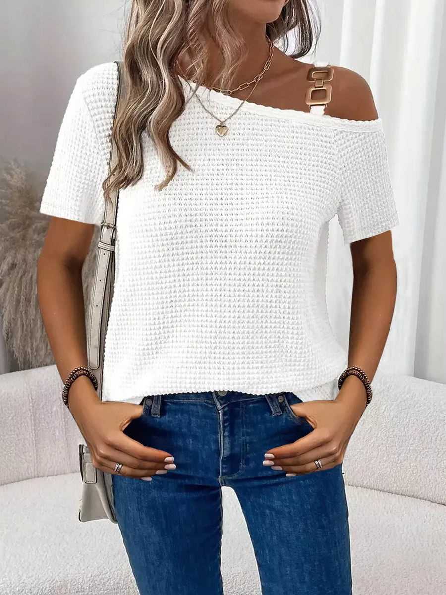 White waffle knit one-shoulder t-shirt with gold buckle detail on strap.