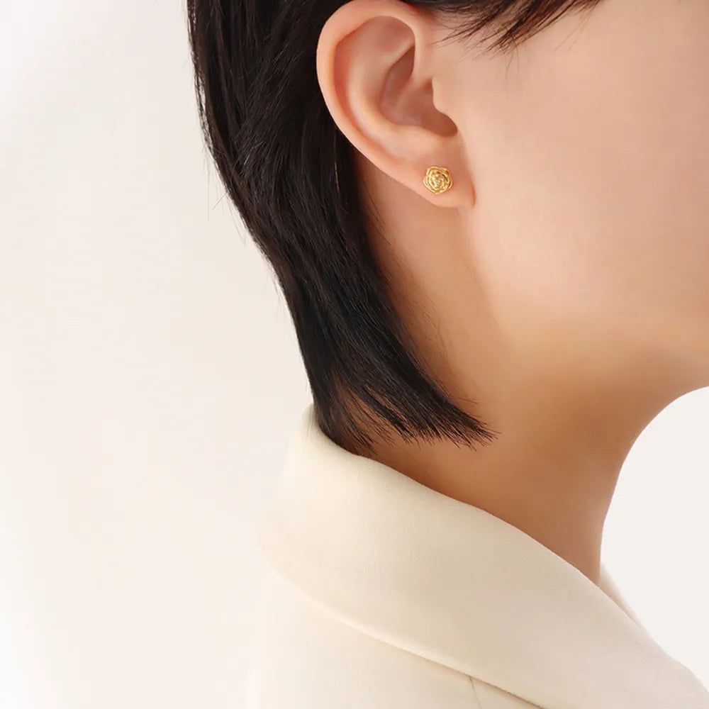 Gold rosebud stud earrings with sculpted petal detail.