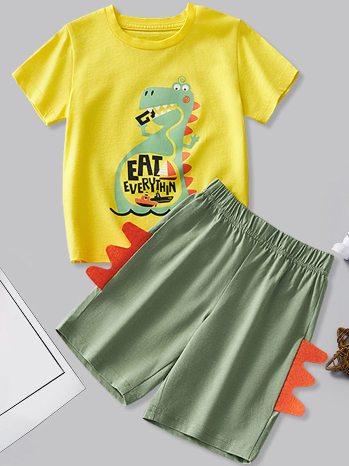 Yellow dinosaur graphic tee and green shorts set with orange spikes.
