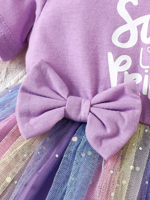Lavender baby dress with rainbow tulle skirt, sequin accents, and a large bow detail.