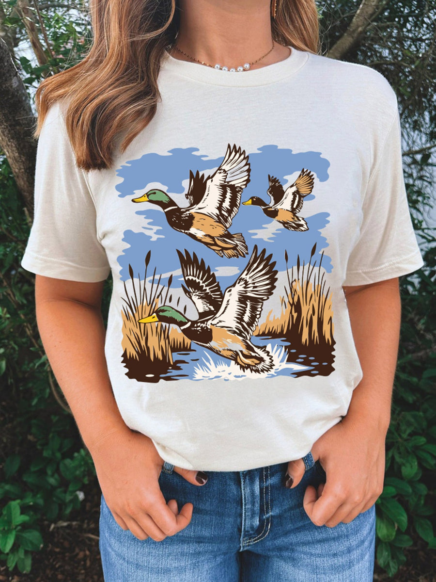 Cream cotton short-sleeve tee with a graphic print of ducks flying over water and reeds.