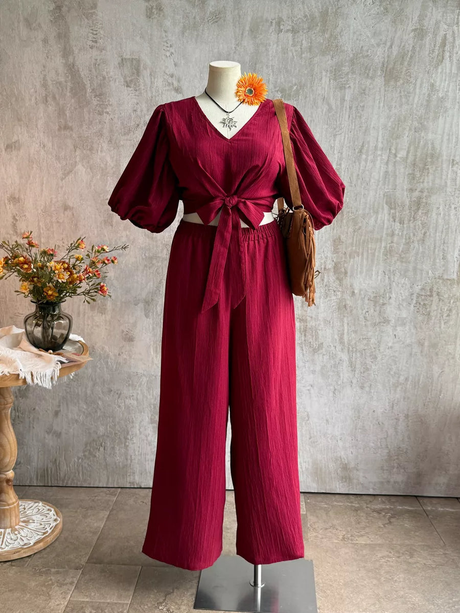 Deep red textured tie-front crop top with balloon sleeves and wide-leg pants set.