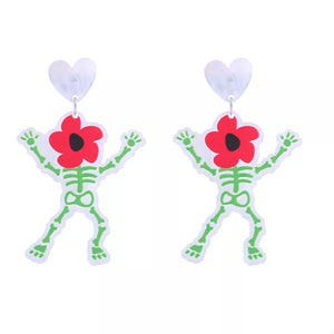 Spooky skeleton dangle earrings with red flower heads and white heart tops.
