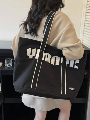 Black drawstring shoulder bag with bold white lettering and white piping detail.