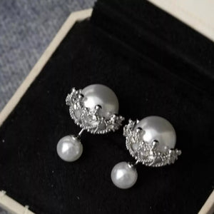 Crown-inspired pearl stud earrings with dangling pearls and intricate silver settings.