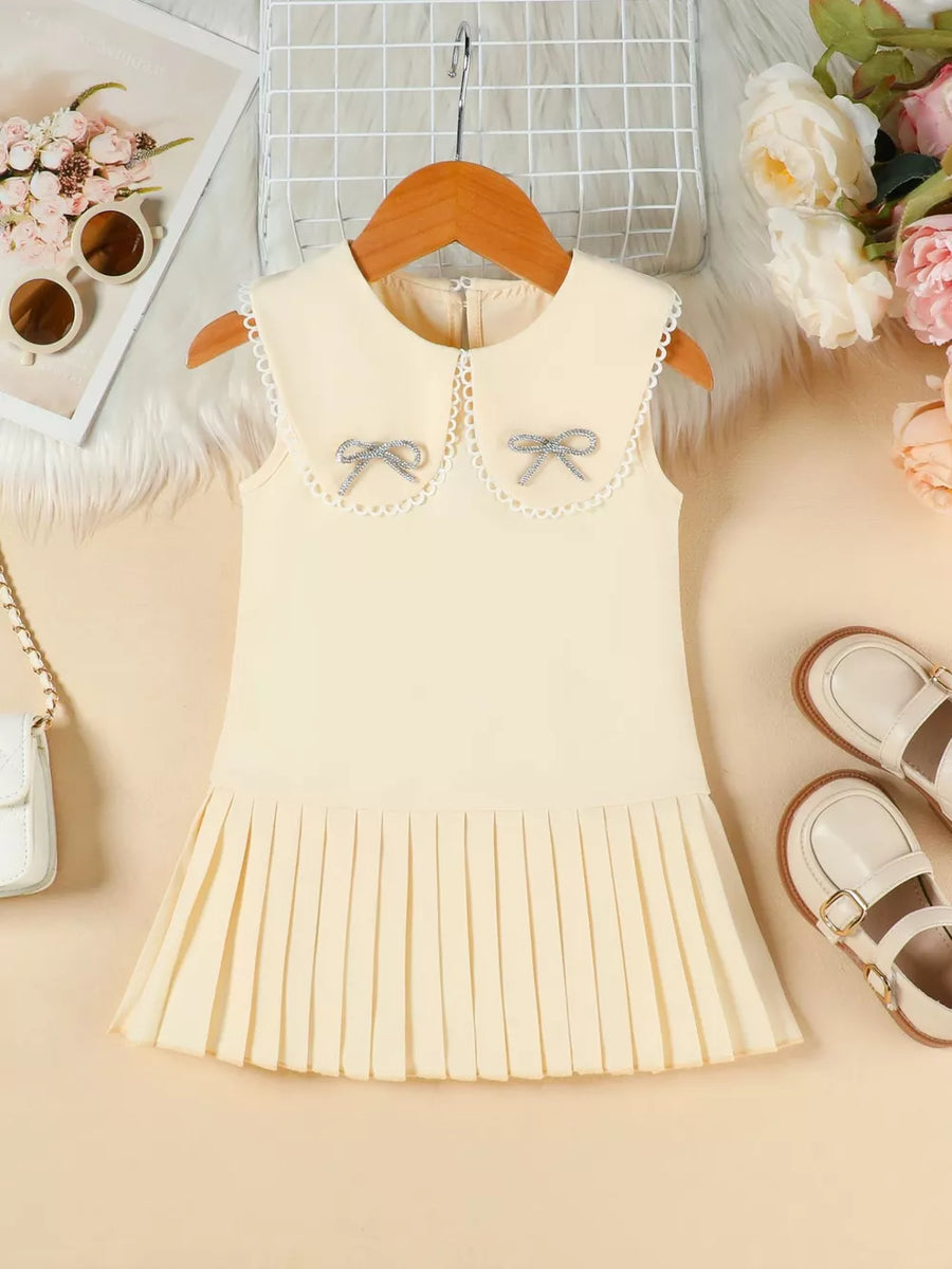 Apricot toddler dress with lace collar, two bows, and pleated skirt.