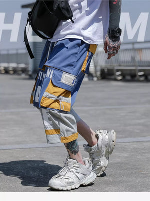 Color block utility cargo pants in light blue and yellow with multiple pockets and drawstring details.