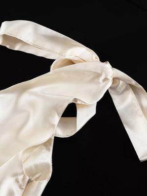 Cream satin slip dress with adjustable tie straps and a side zipper.