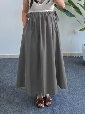 Gray a-line midi skirt with pockets and tie details, styled casually.