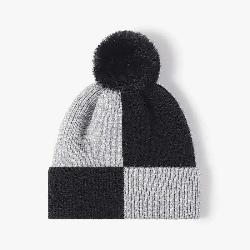 Colorblock knit beanie with black pom and checkerboard pattern in black and grey.