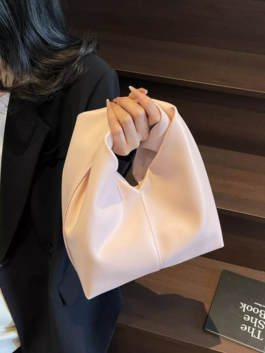 Blush pink leather shoulder bag with knot handle and classic carryall shape