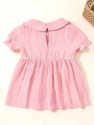 Pink cotton baby dress with Peter Pan collar, puff sleeves, and gathered waist.