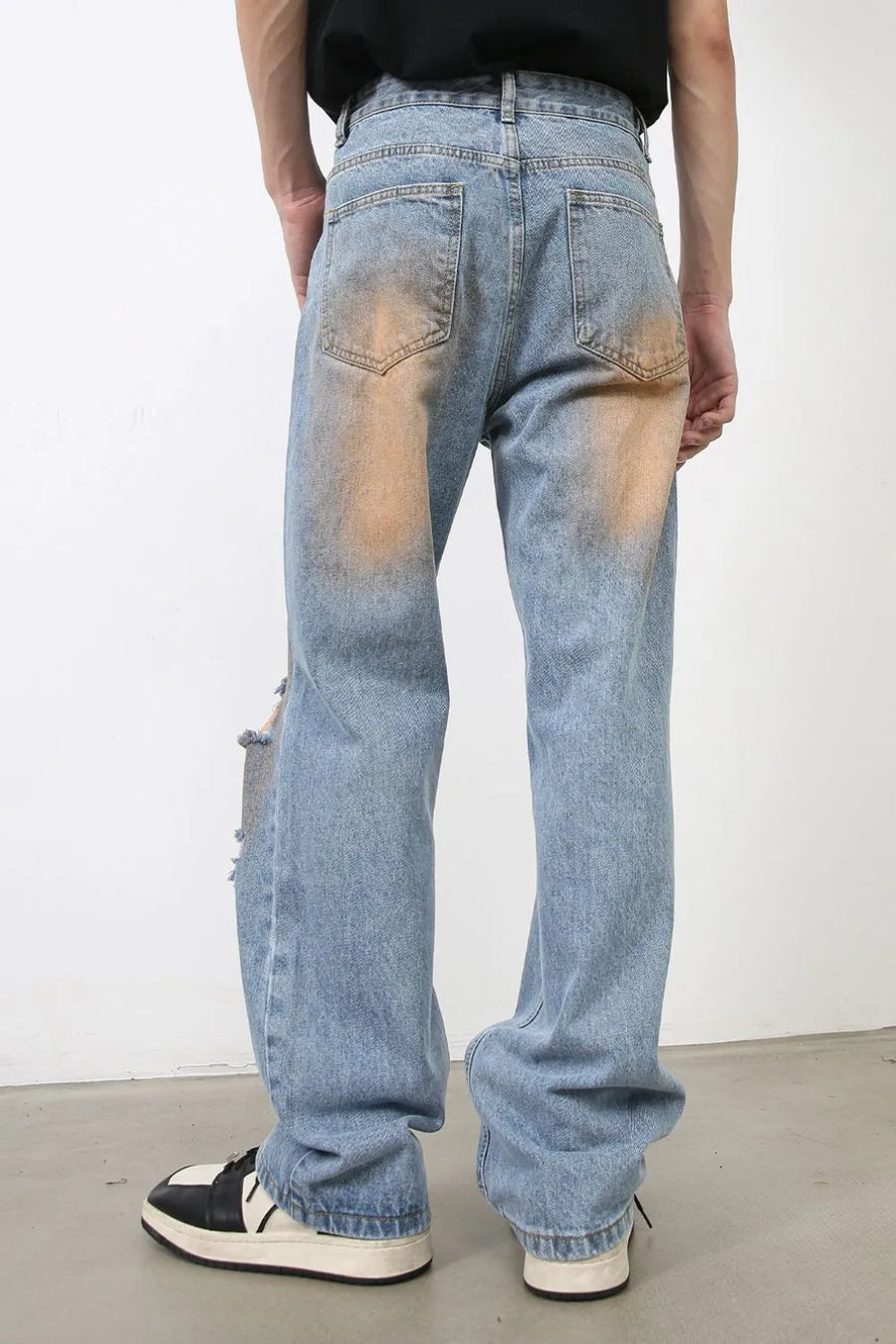 Light blue faded wash wide leg jeans with distressed details and orange bleach accents.