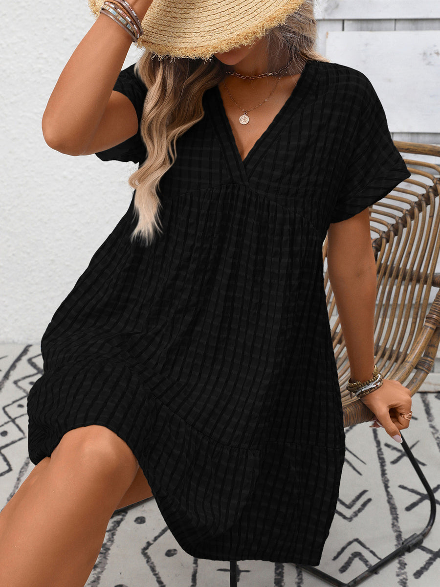 Black plaid V-neck mini dress with short sleeves and tiered skirt.