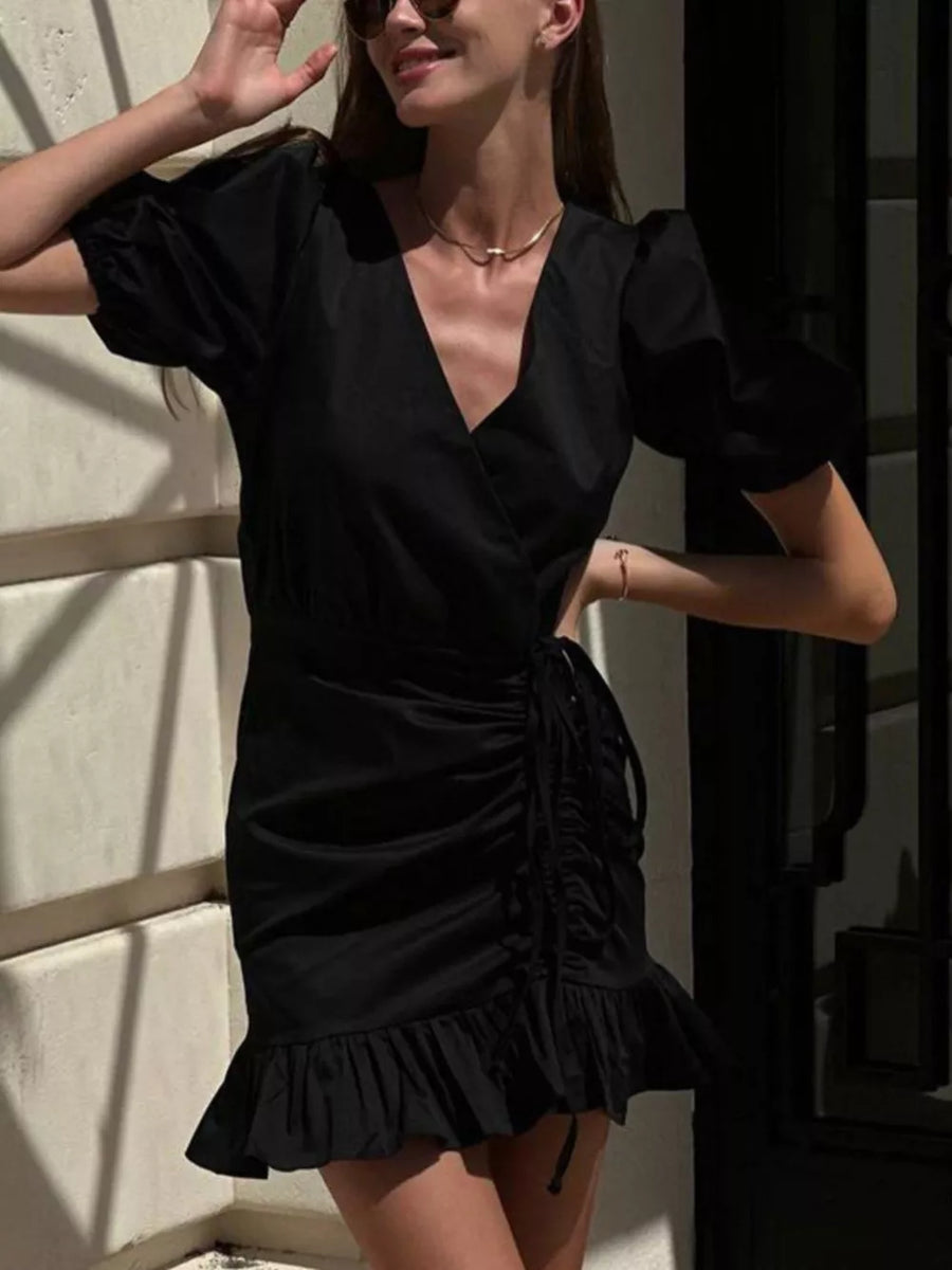 Black wrap dress with puff sleeves, V-neck, ruched side detail, and ruffled hem.