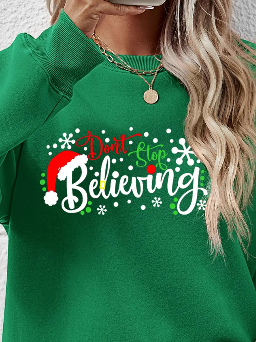 Green crewneck sweater with "Don't Stop Believing" graphic and Santa hat detail