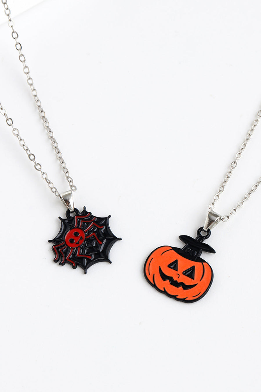 Spooky Season enamel pendant necklaces with spiderweb and jack-o-lantern charms.