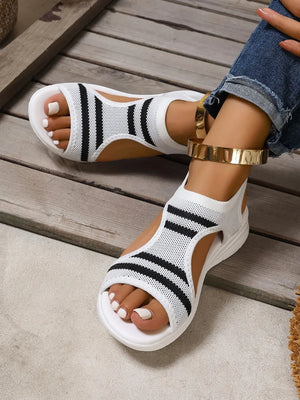 White knit sport sandals with black stripes and a white sole.