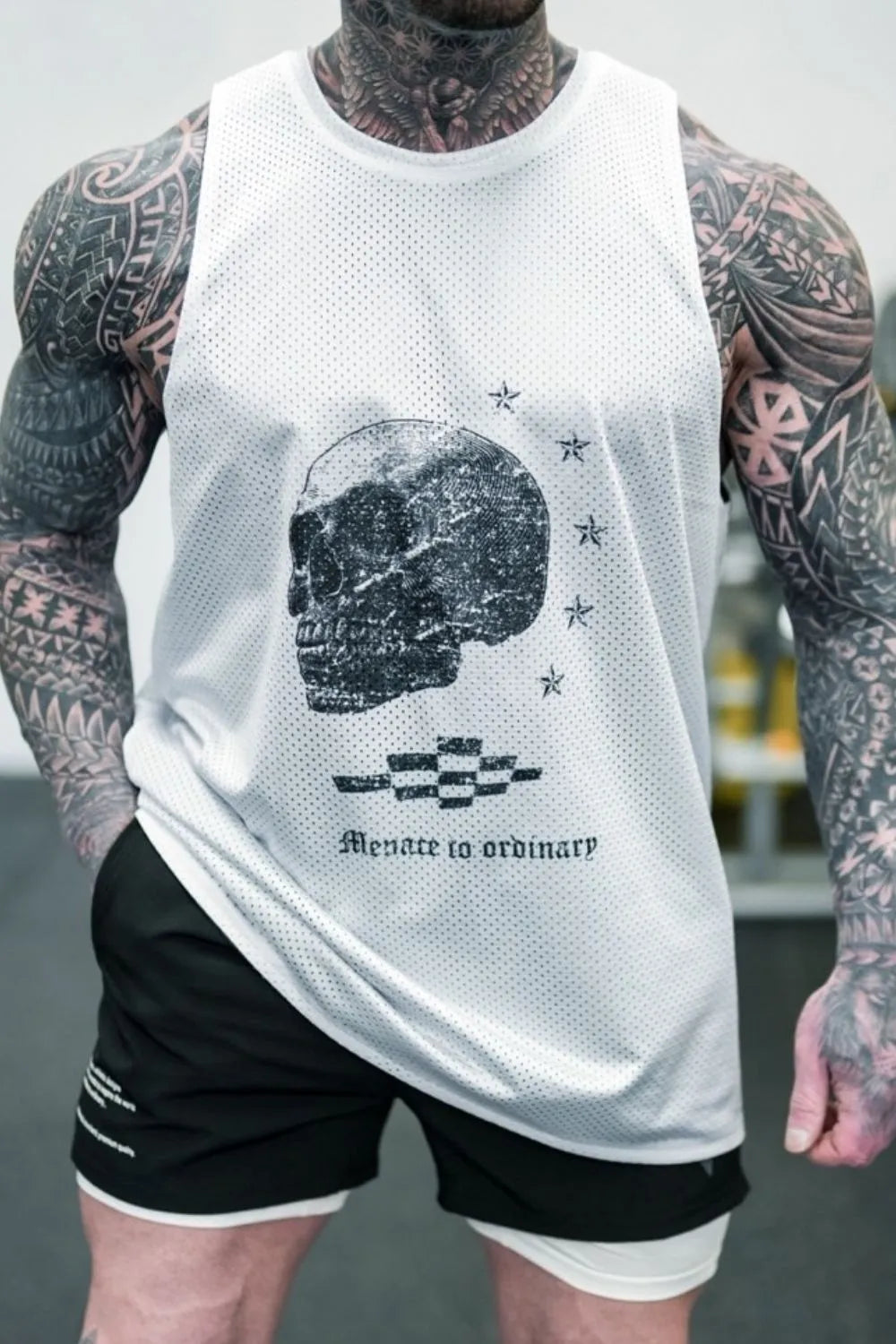 White perforated tank top with black skull graphic and text.