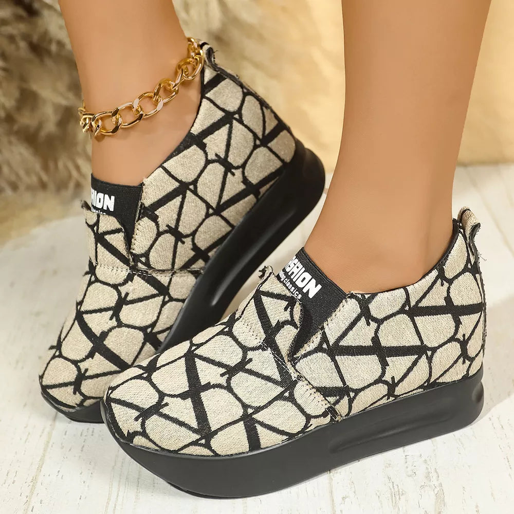 Geometric patterned beige and black slip-on sneakers with platform sole and gold anklet.