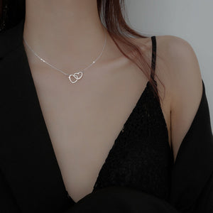 Silver interlocking heart pendant necklace on a delicate chain.