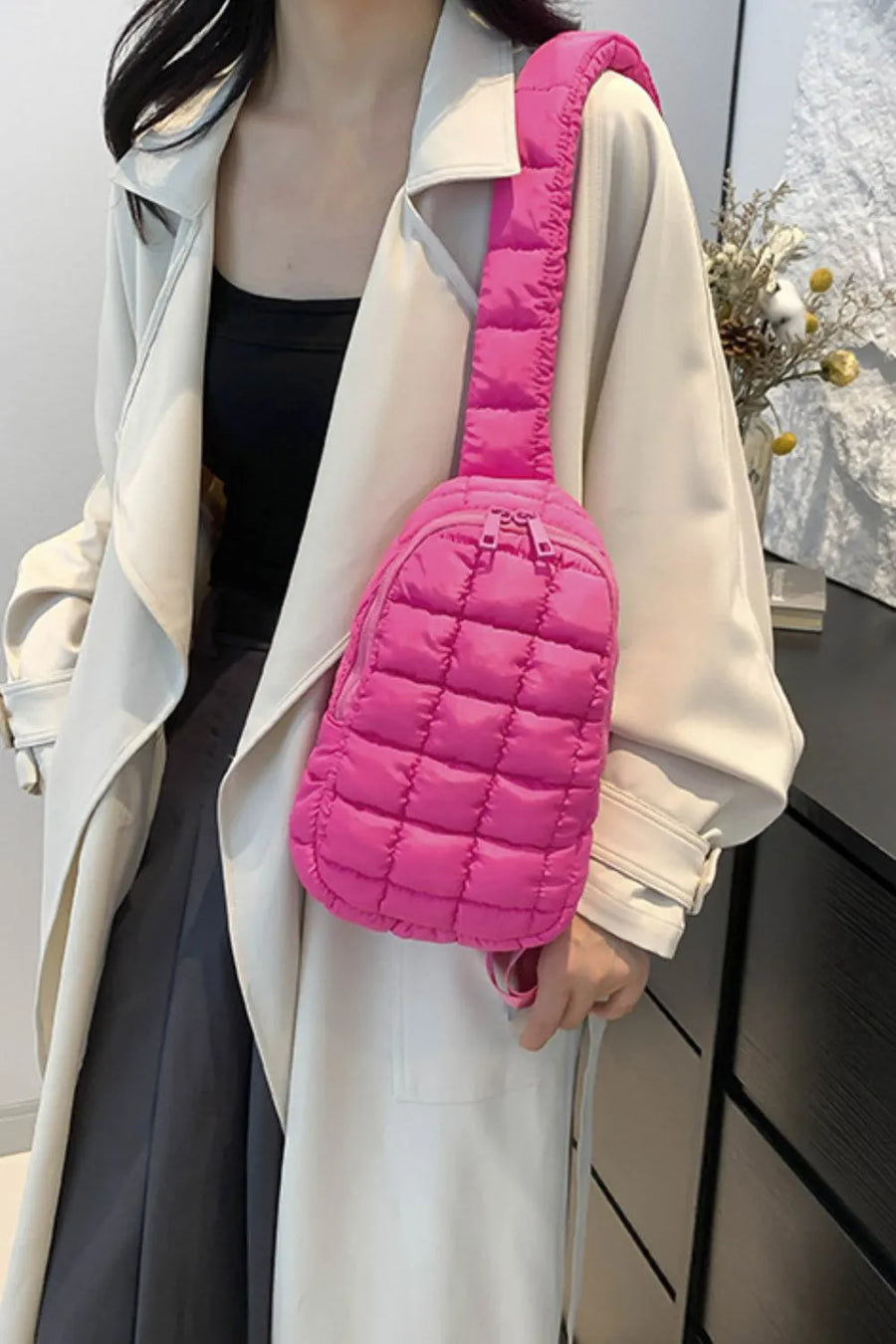 Padded sling bag in hot pink with quilted pattern and top handle, worn crossbody.
