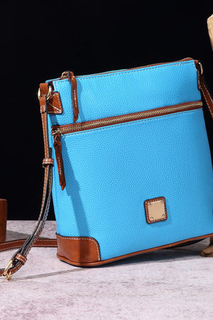 Pastel blue leather crossbody bag with brown trim and gold hardware.