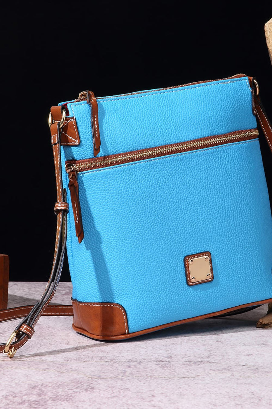 Pastel blue leather crossbody bag with brown trim and gold hardware.