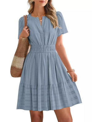 Textured light blue V-neck tiered dress with smocked waist and short sleeves.