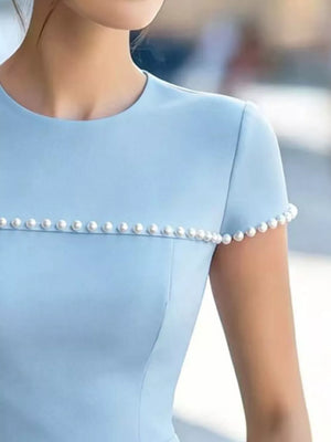 Light blue t-shirt with pearl embellishments on the neckline and sleeves.