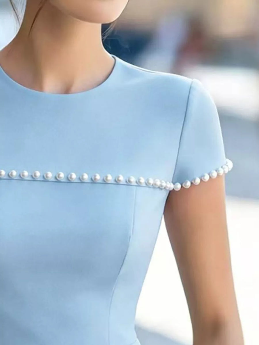 Light blue t-shirt with pearl embellishments on the neckline and sleeves.