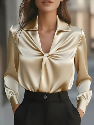 Elegant satin blouse in pastel yellow with ruched front and long sleeves.