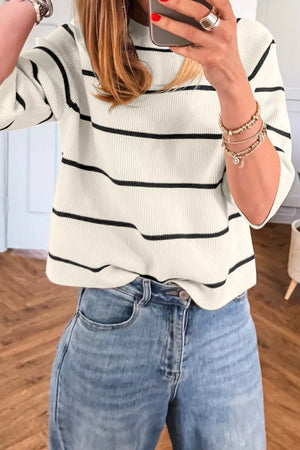 White and black striped ribbed knit top with a mock neck, styled with denim.