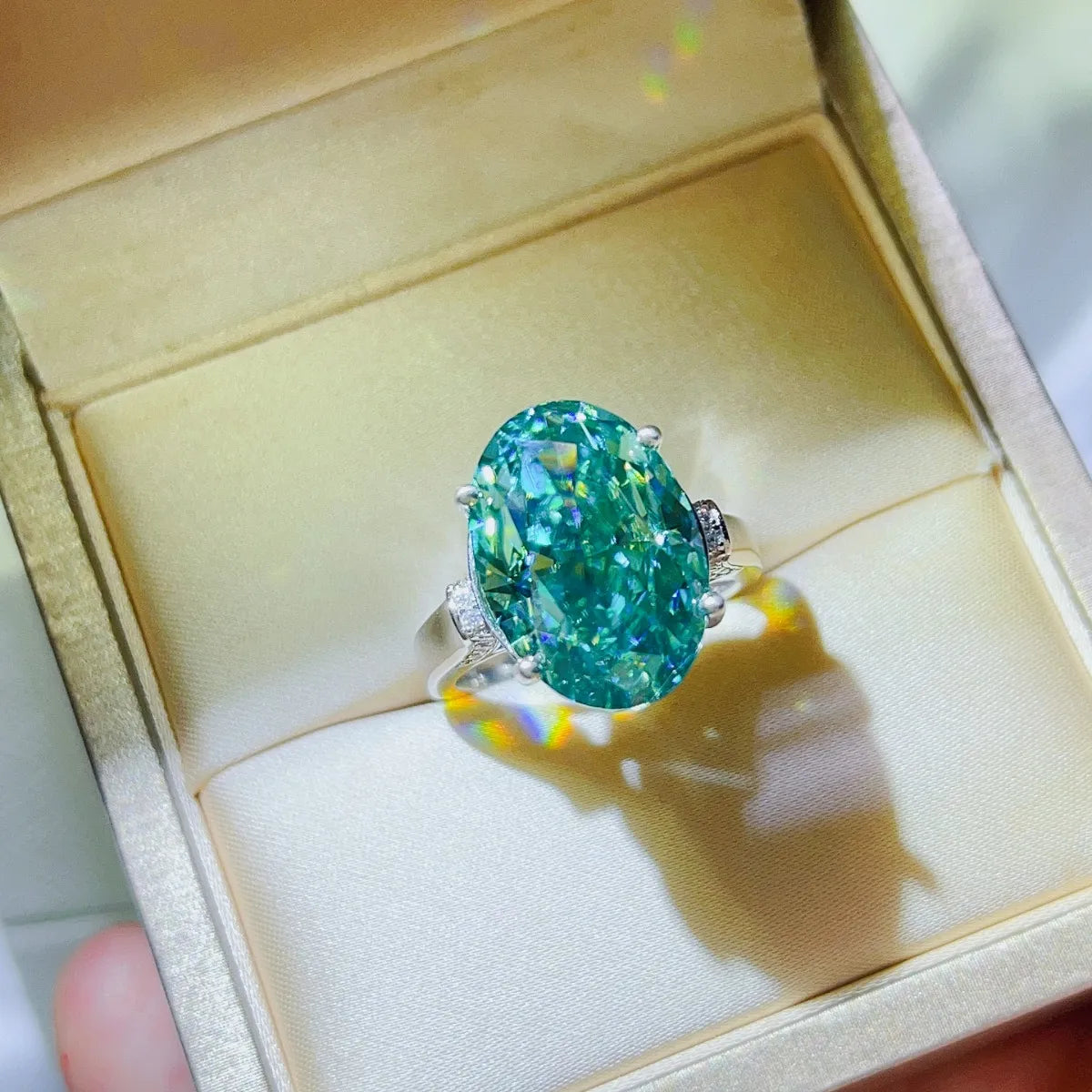 Emerald cut turquoise moissanite cocktail ring with diamond accents on a silver band.