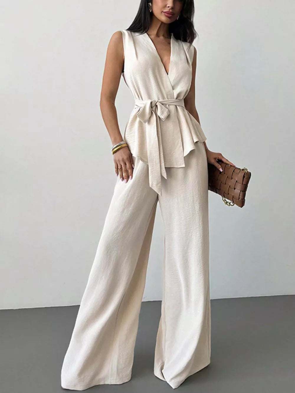 Sleeveless wrap top and wide-leg pants set in cream polyester with a tie waist.