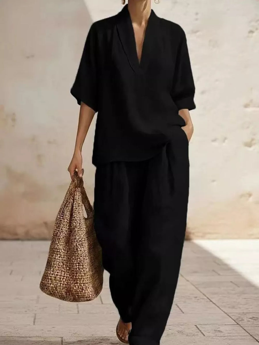 Black half-sleeve top with V-neck and wide-leg pants set, styled with a straw bag.
