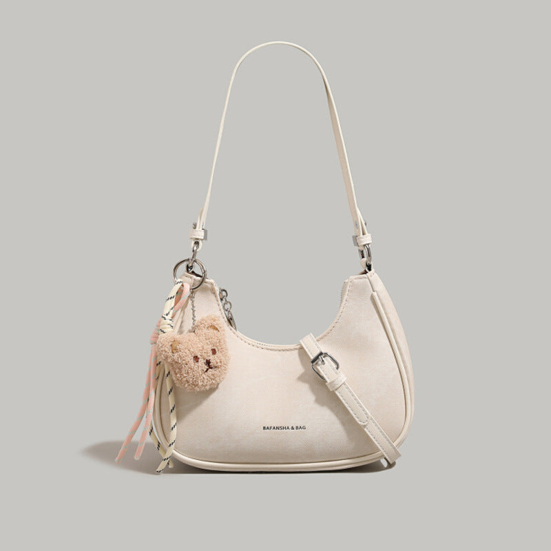 Mini crescent shoulder bag in cream with adjustable strap and teddy bear charm