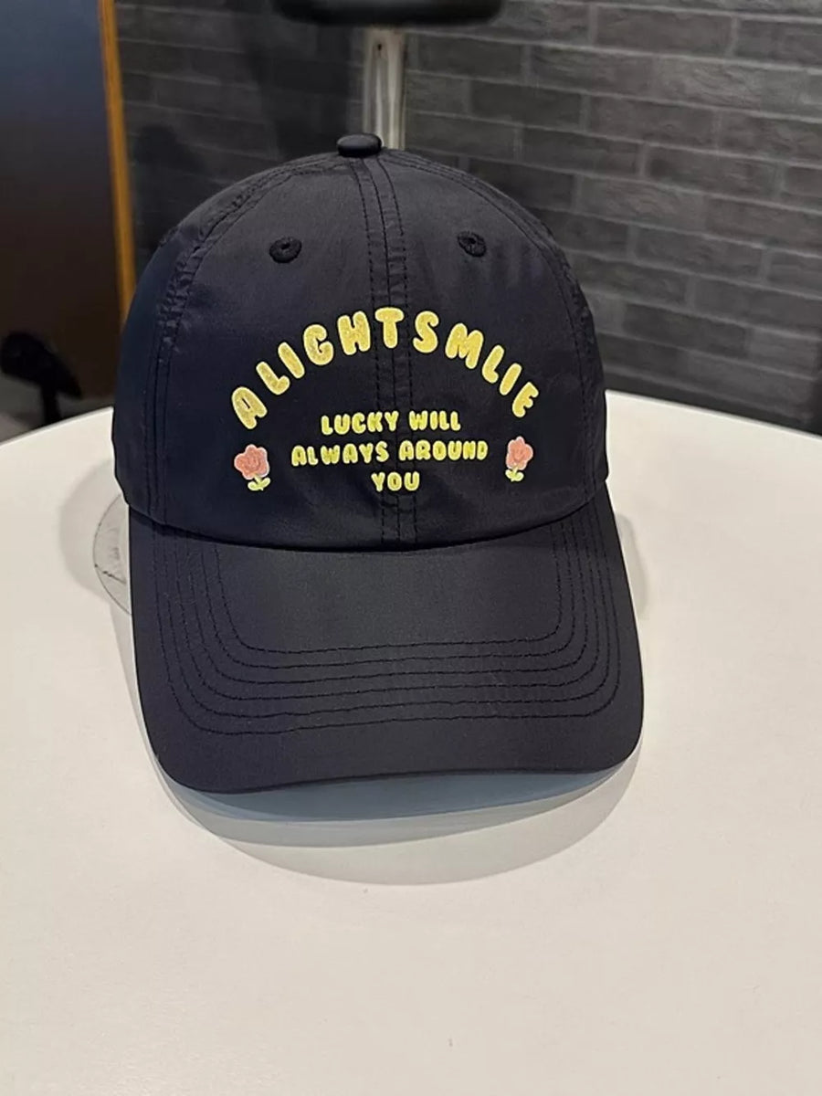 Black baseball cap with yellow text and floral embroidery.