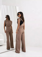 Tan satin cowl neck two-piece set with asymmetrical wrap skirt detail and wide leg pants.