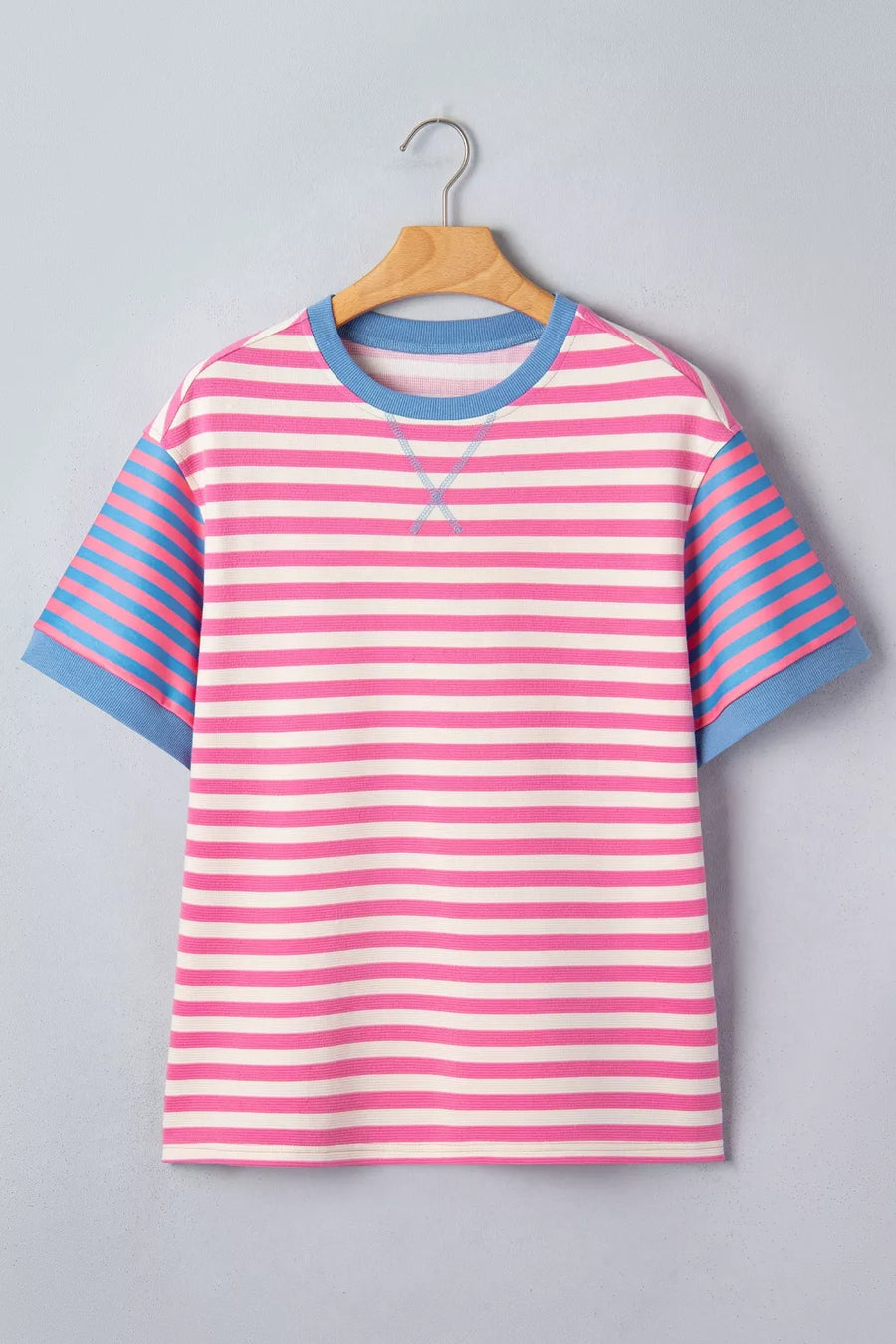 Short sleeve t-shirt with pink and white horizontal stripes, blue striped sleeves, and blue crew neck.