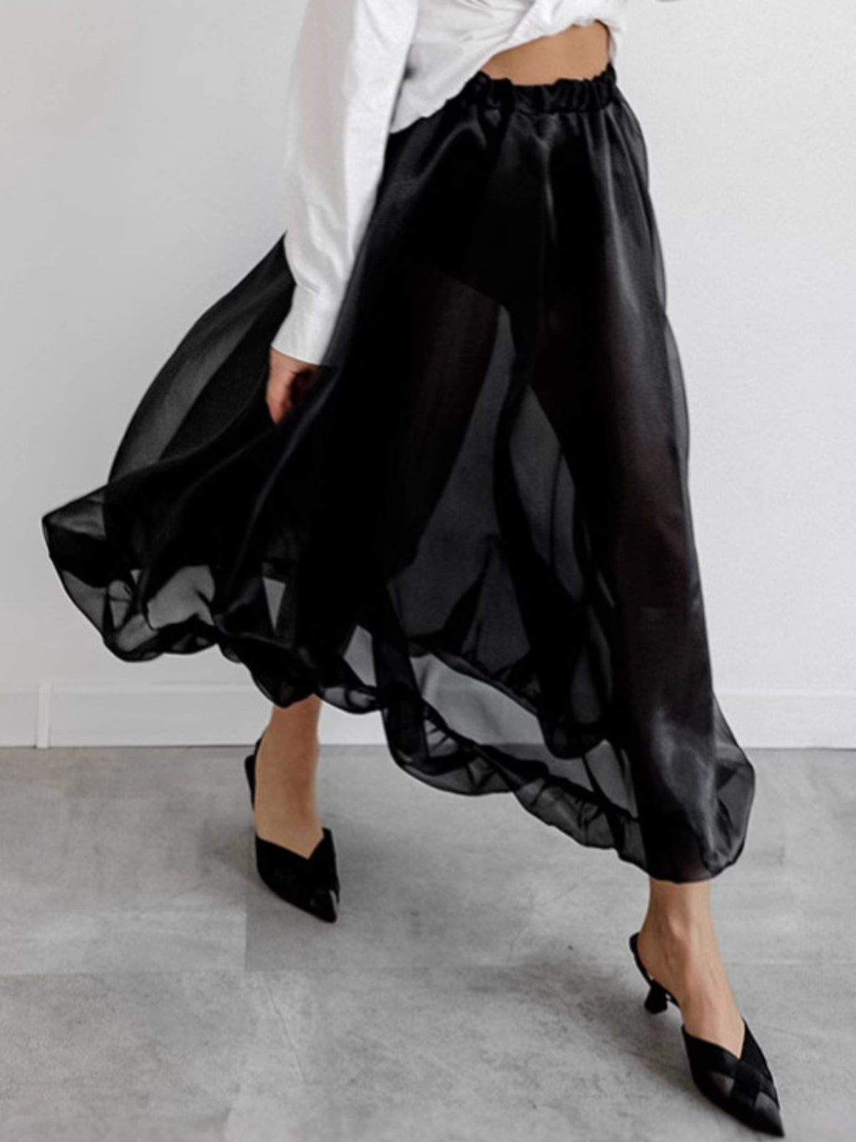 Black midi skirt with sheer overlay and ruffled hem, styled with a white shirt.