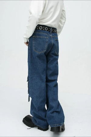 Medium wash denim cargo pants with buckle strap details and a wide leg cut.