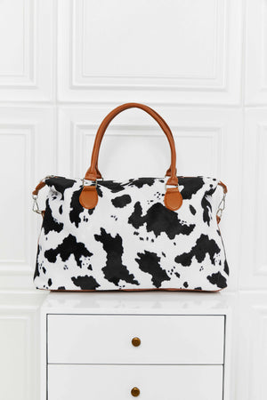 Satchel bag with cow print, brown leatherette handles and trim.