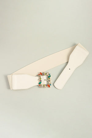Ivory elasticated belt with jeweled buckle and faux leather trim.