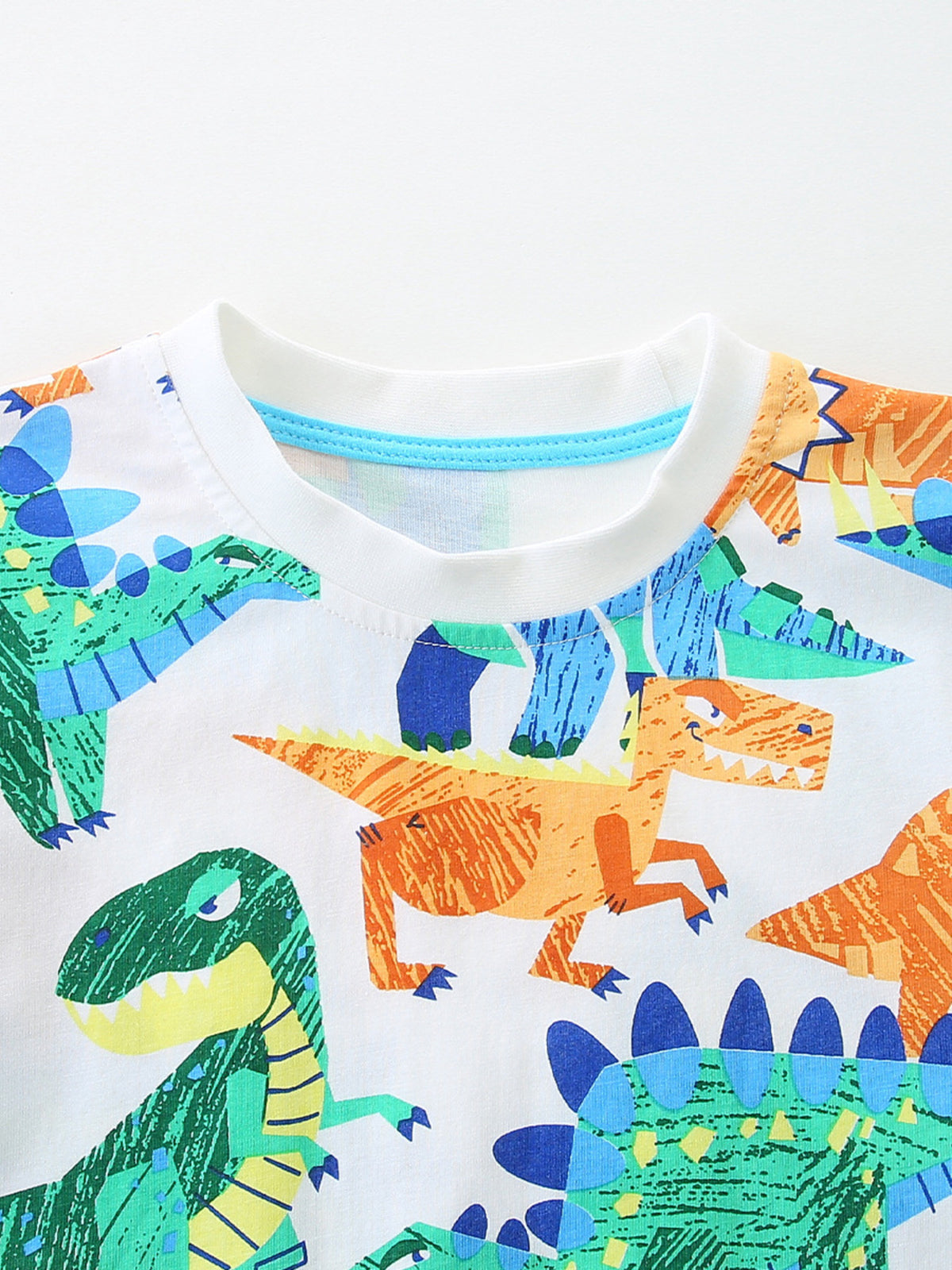 Children's white cotton crew neck t-shirt with a colorful dinosaur print.