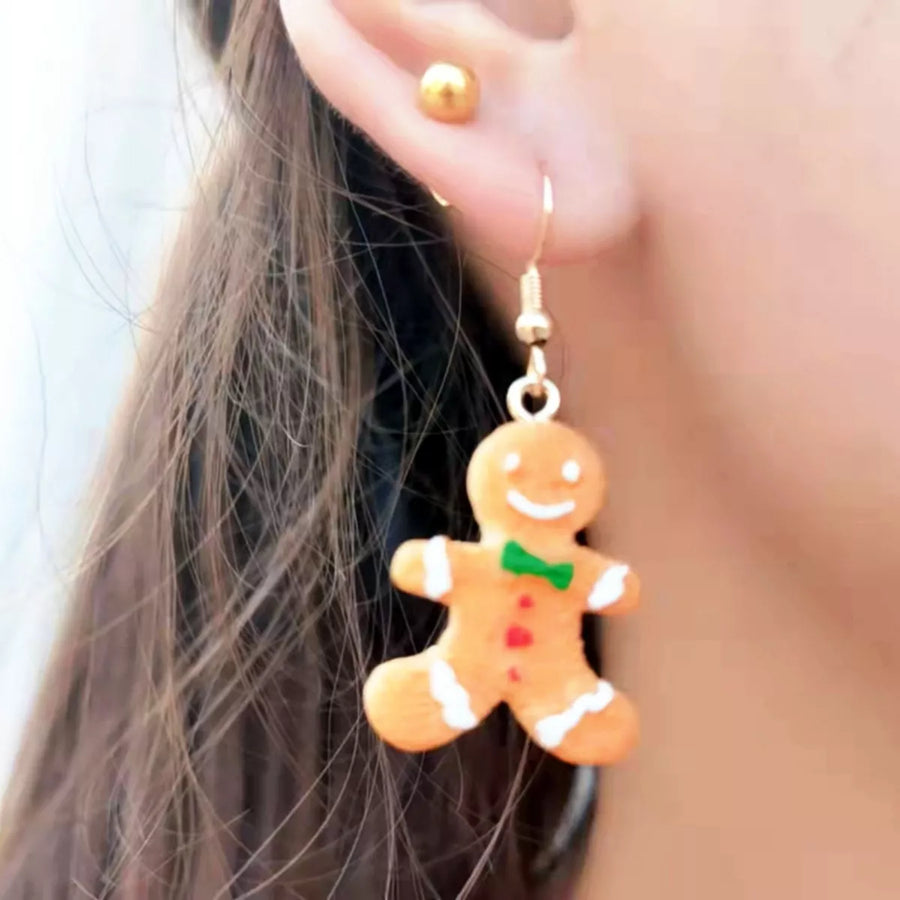 Gingerbread man holiday earrings with green bow and red heart details.