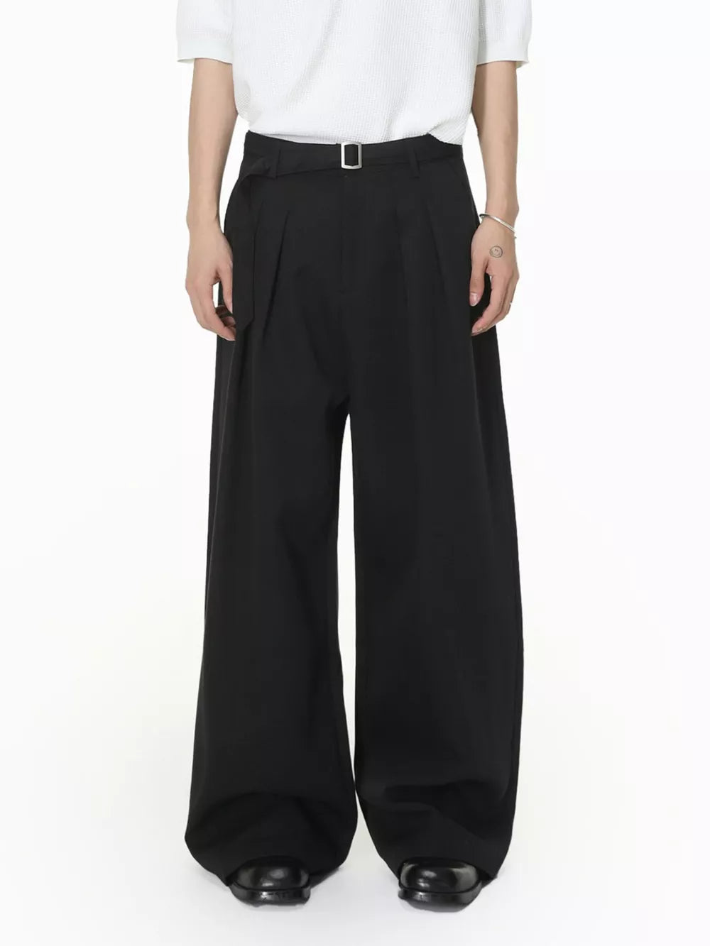Black wide-leg pleated sweatpants with a belt and silver buckle.