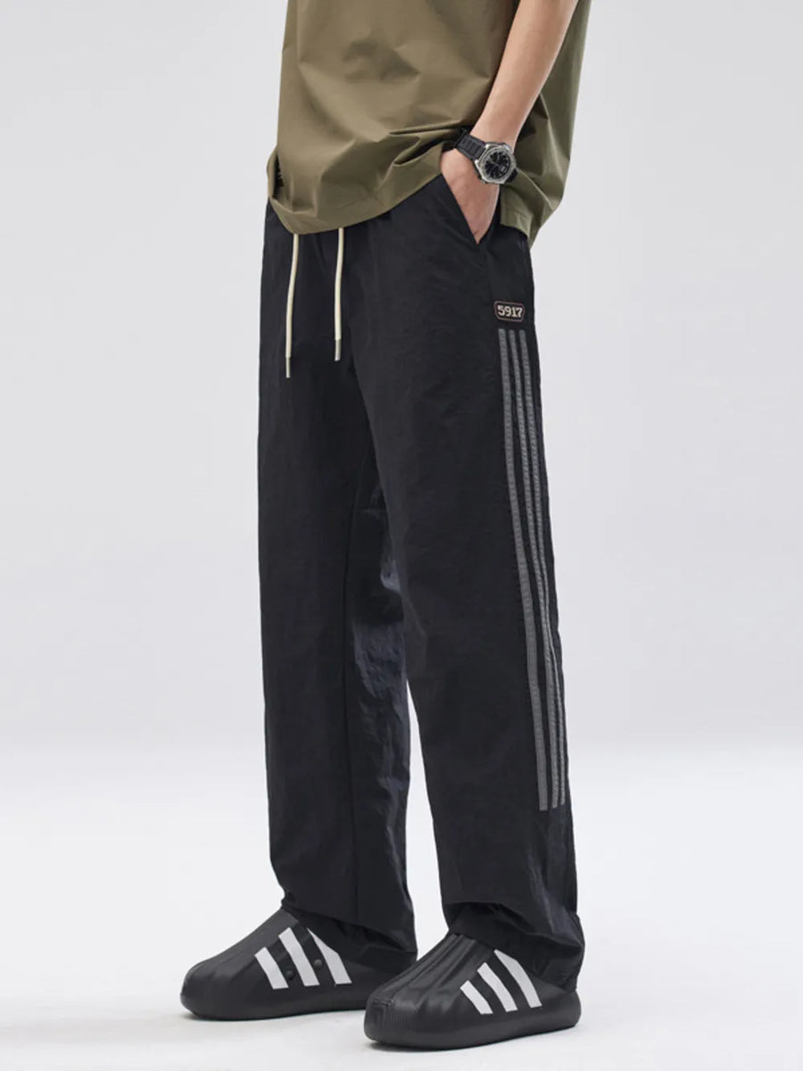 Black casual drawstring sweatpants with side stripe detail and loose fit.